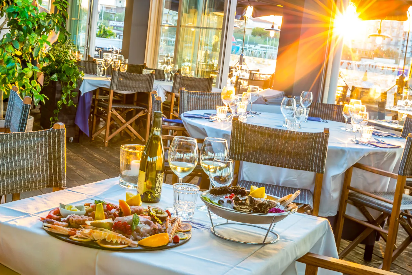 Il tavolo allestito con gli antipasti di pesce e i calici, nella luce del tramonto