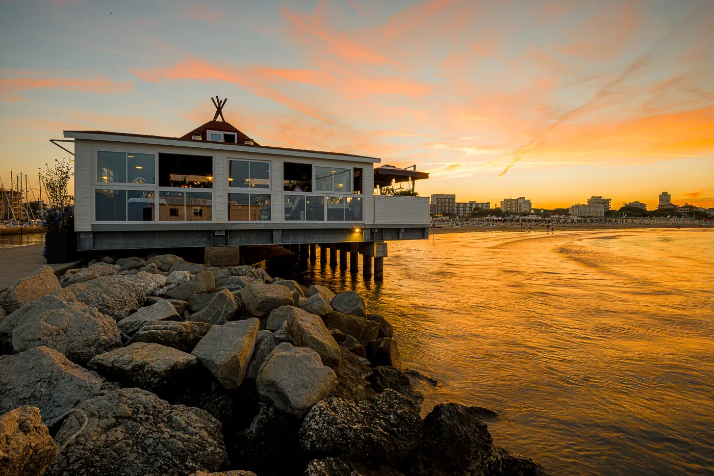 Il Ristorante Kalumet sul molo di Milano Marittima al tramonto, con la scogliera e l’acqua che trattiene il colore