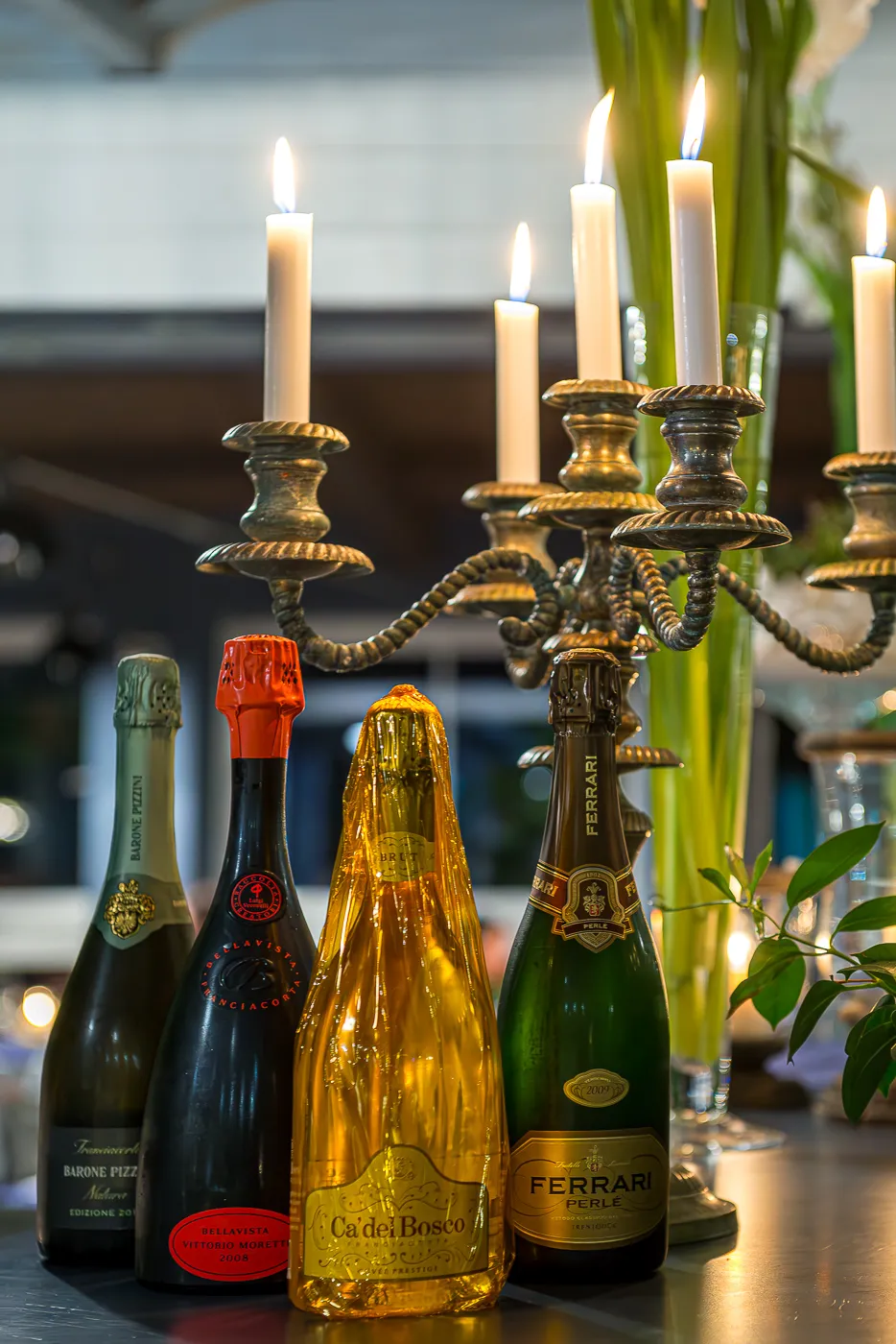 Candelabro con le candele accese e le bottiglie di bollicine