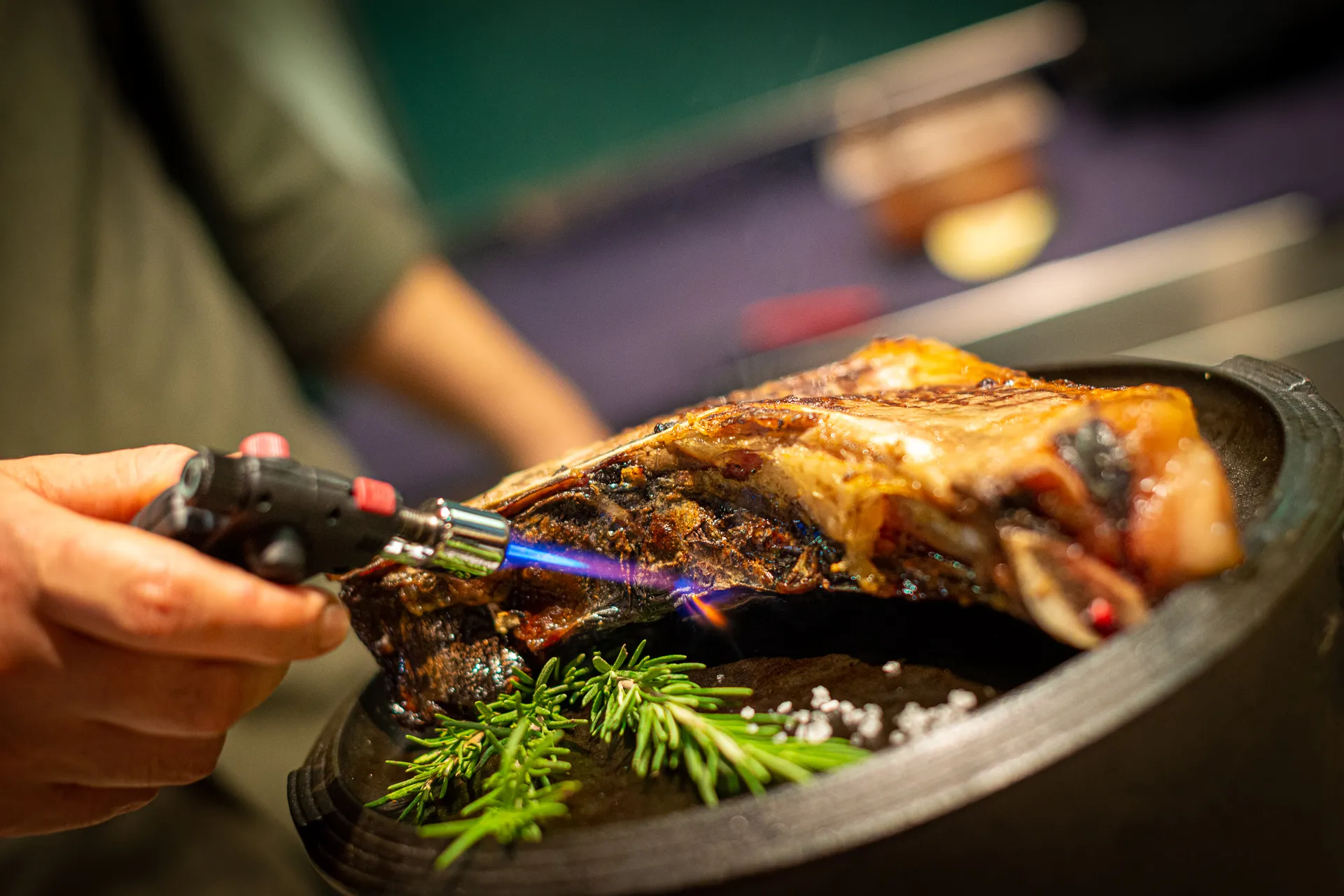 Le mani dello chef al cannello sulla carne