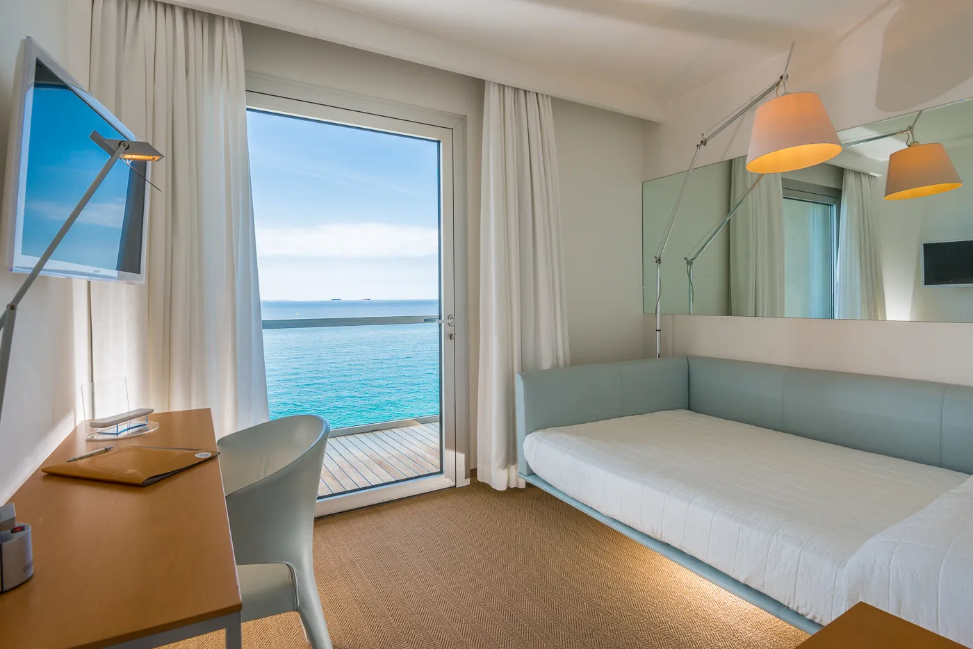 Il letto della camera vista mare, con il golfo oltre la vetrata