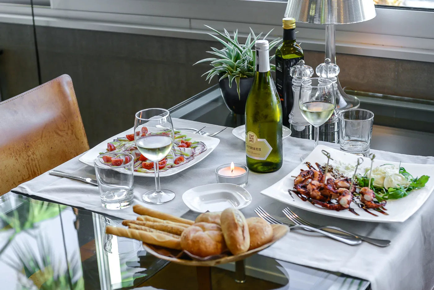 Tavolo apparecchiato con crudi di pesce e vino bianco