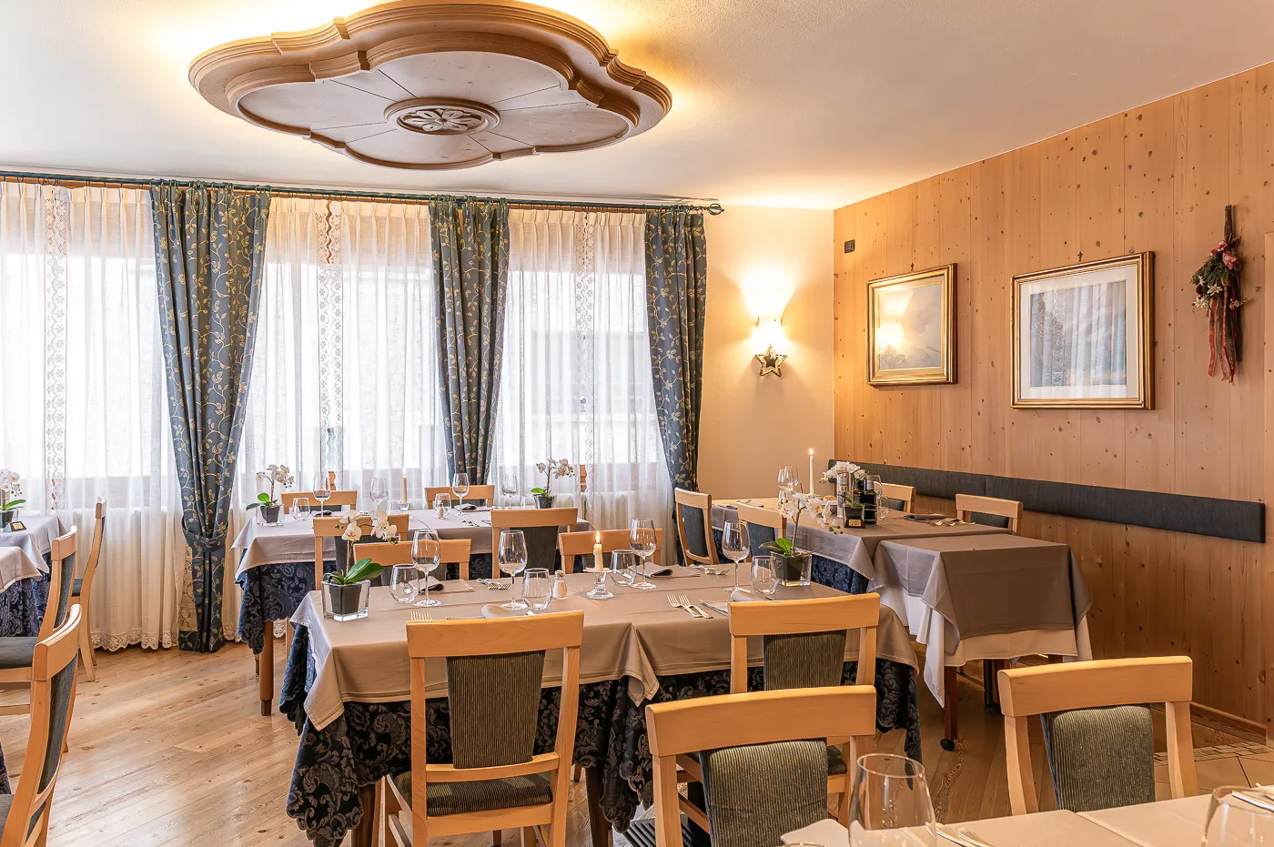 La sala da pranzo con i tavoli apparecchiati e il rosone in legno