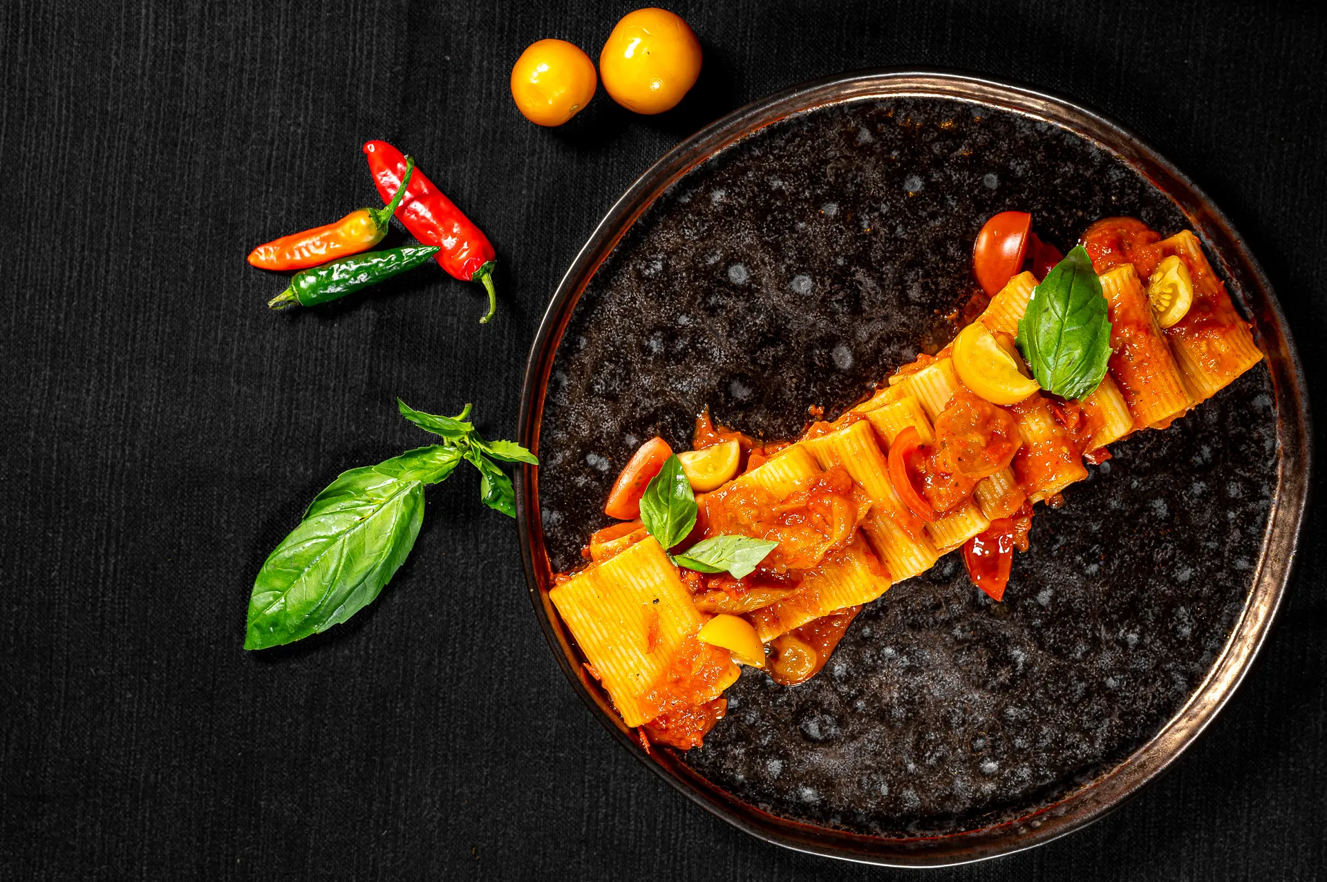 Primo piatto su fondo nero con pomodorini e basilico