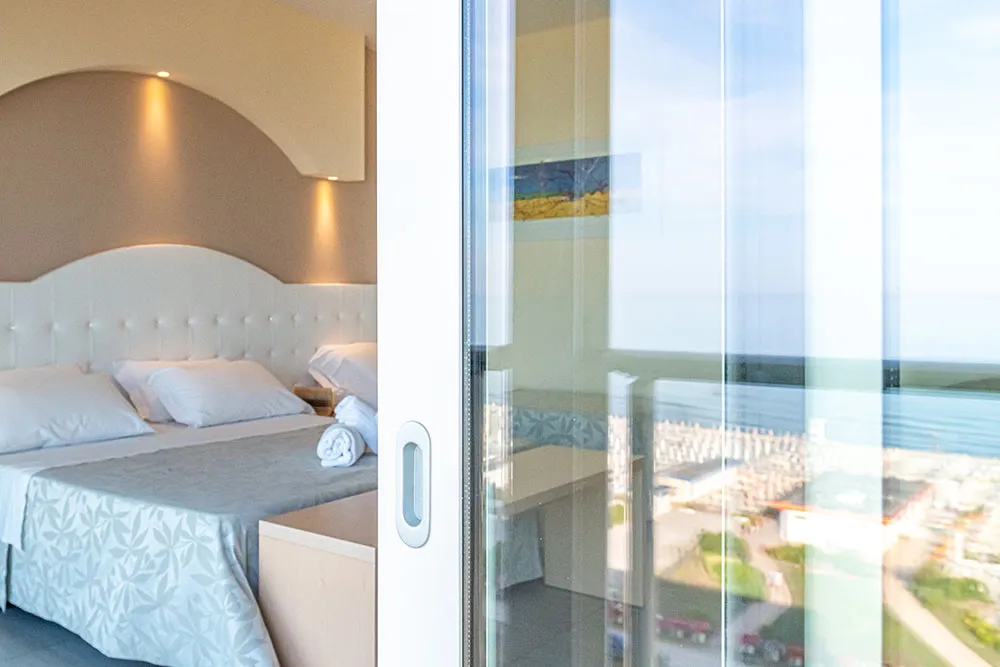 Camera con letto matrimoniale e porta-finestra affacciata sulla spiaggia
