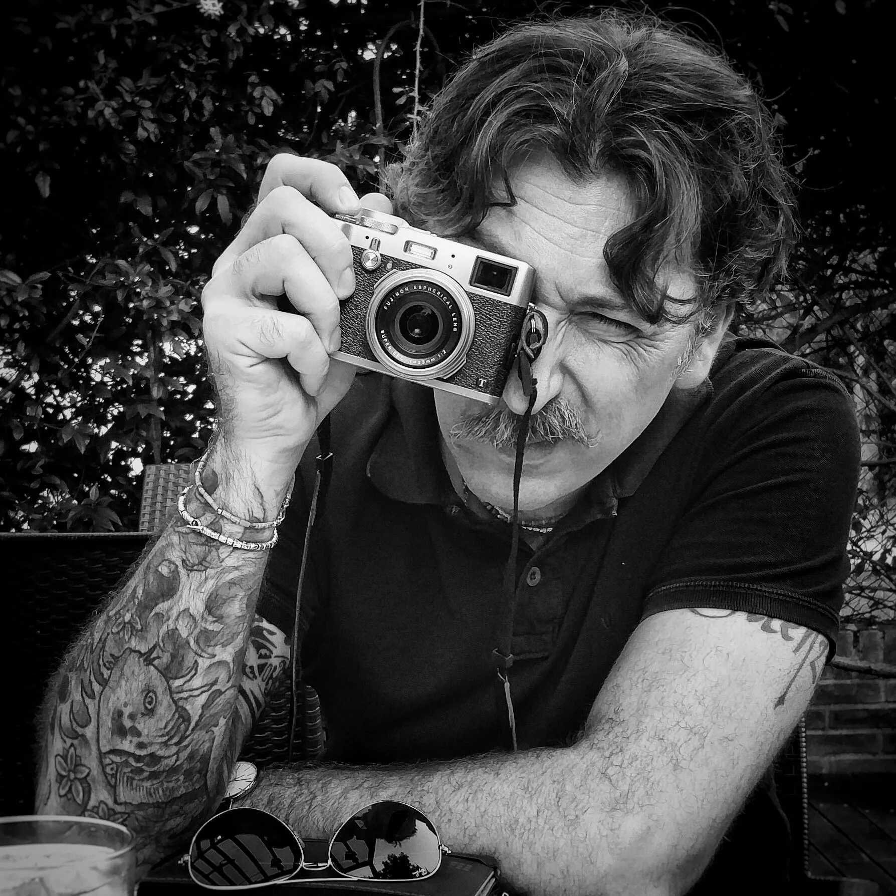 Ritratto in bianco e nero di Vincenzo Basile mentre inquadra con la macchina fotografica