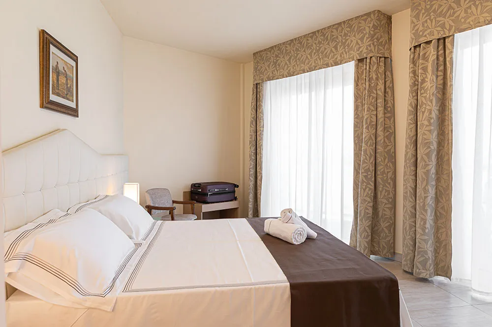 Camera con letto bianco e tende chiare