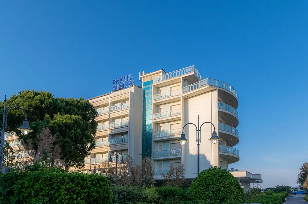 Facciata dell’Hotel Adria tra i pini della pineta di Milano Marittima, con l’insegna sul tetto