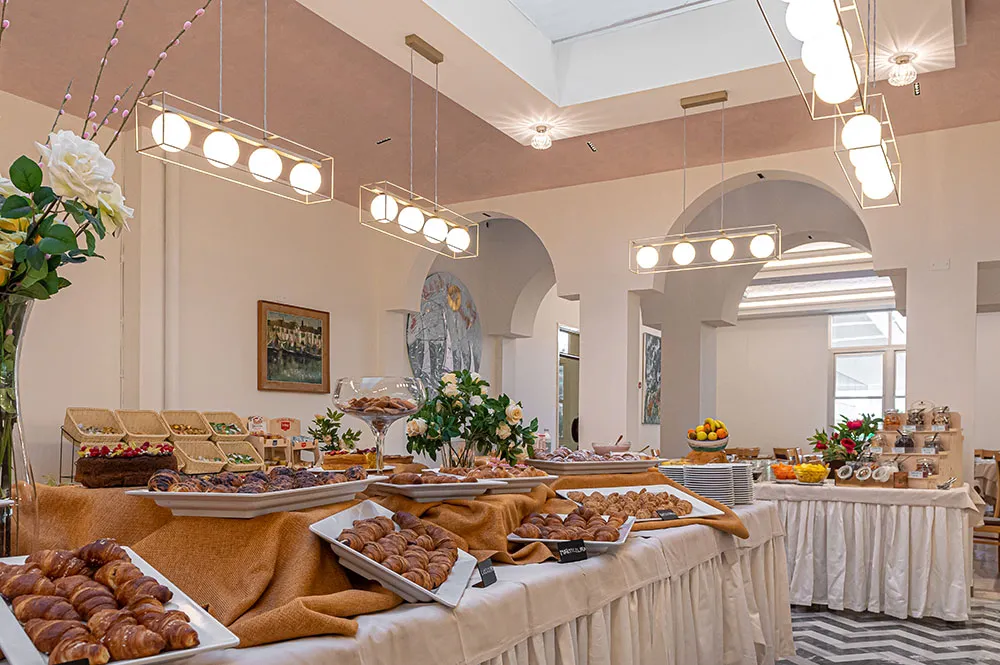 La sala colazione con il buffet allestito e i lampadari accesi