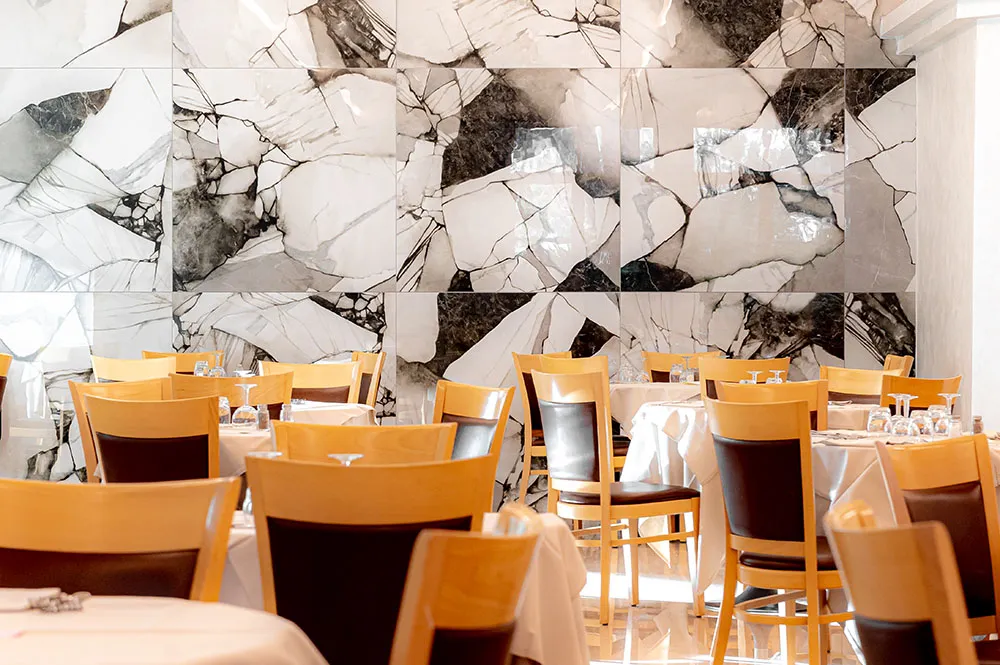 I tavoli della sala ristorante davanti alla parete in marmo