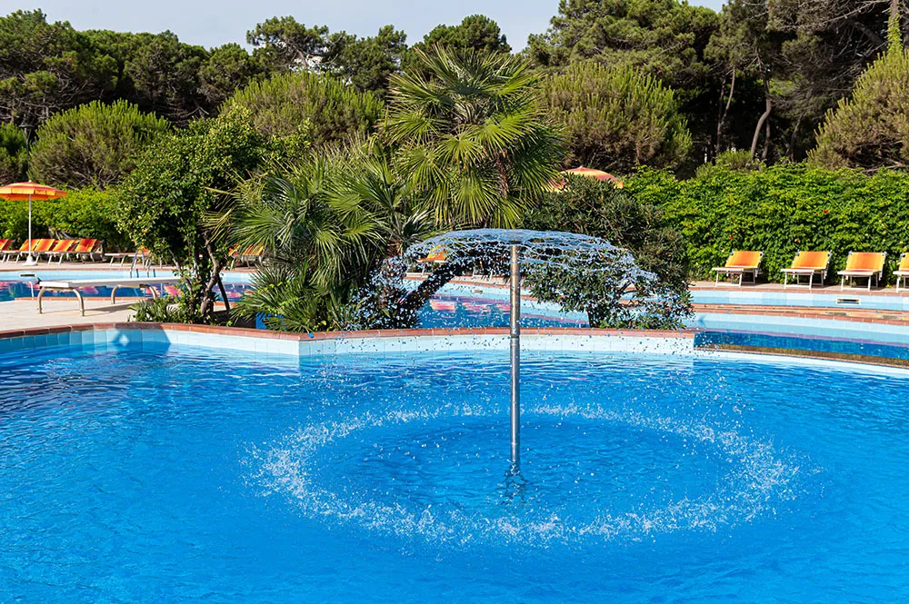 I getti d’acqua della piscina nella cornice della pineta